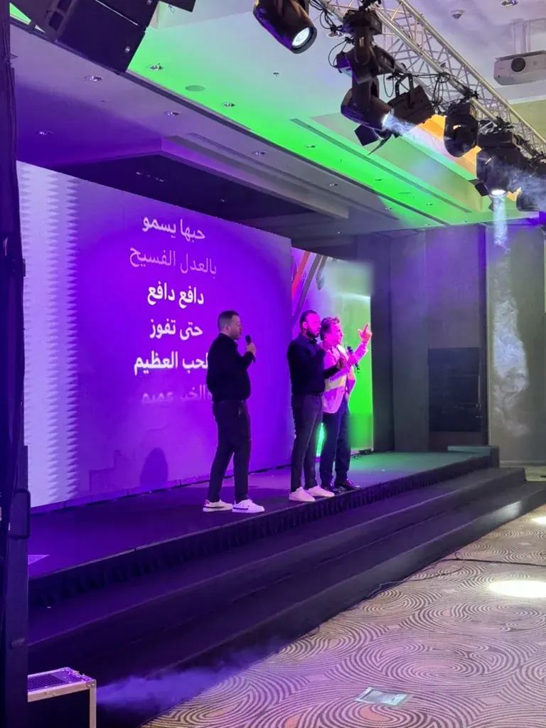 Singers on a lit conference stage with an LED lyrics wall, at a corporate event in Istanbul