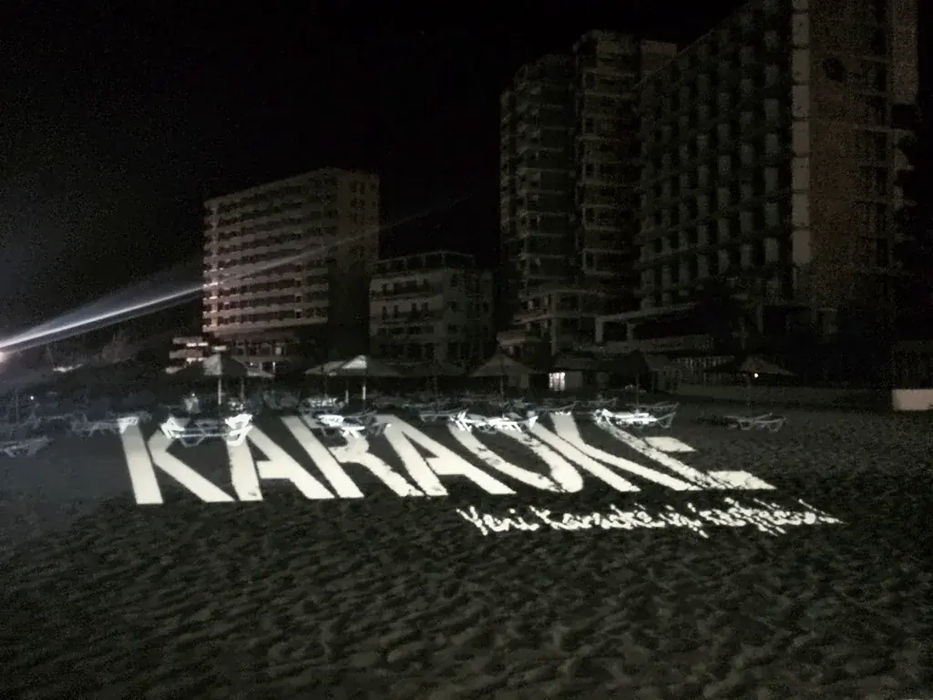 The word KARAOKE projected onto the sand at a beach party, Palm Beach Hotel, Famagusta