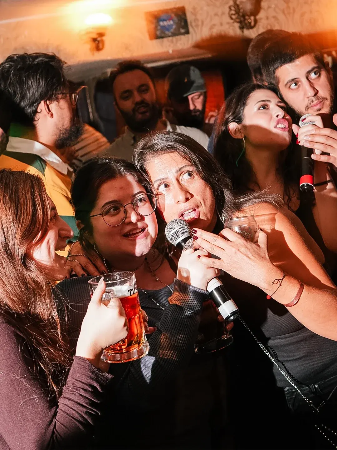 A group of all ages singing into one microphone at The Old Town, Ankara