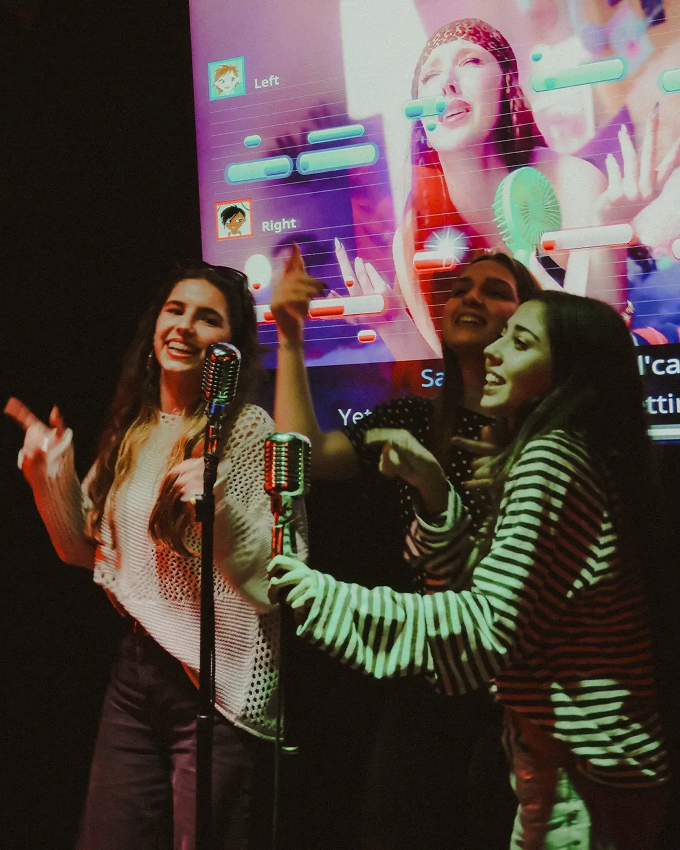 Three friends singing at the mics in front of the lyrics screen