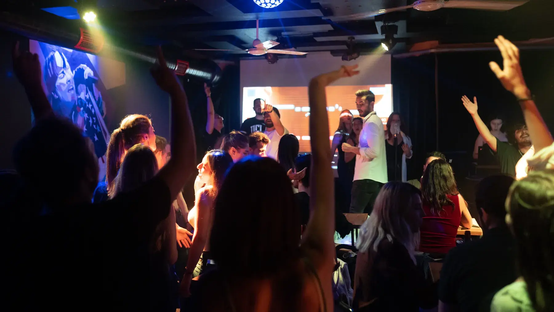 Guests with their hands up in front of the karaoke screen at Yazı Tura Barcade, Istanbul